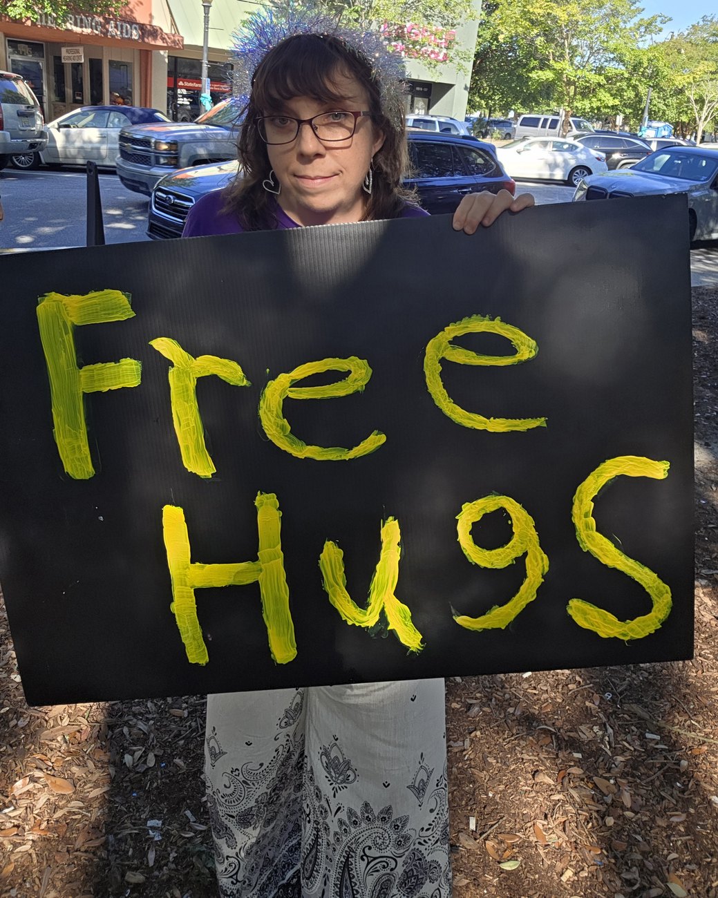 Sherry of Zenfull Heart holding her hand painted Free Hugs sign at the Pensacola market