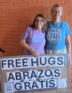 Friends of Zenfull Heart wearing the Source Energy Loading and Let's Be Better Humans tees holding the Free Hugs sign